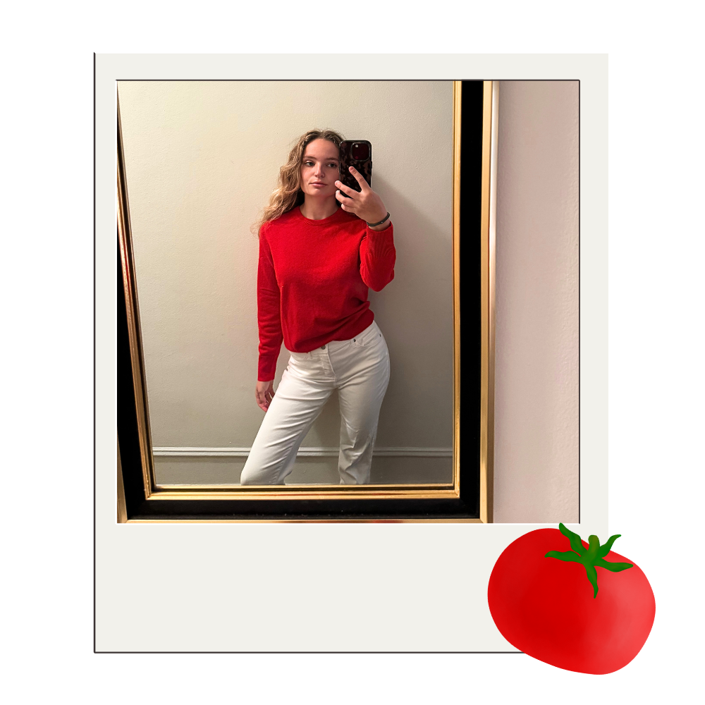 author posing in front of a mirror with the tomato red version of naadam's original sweater on