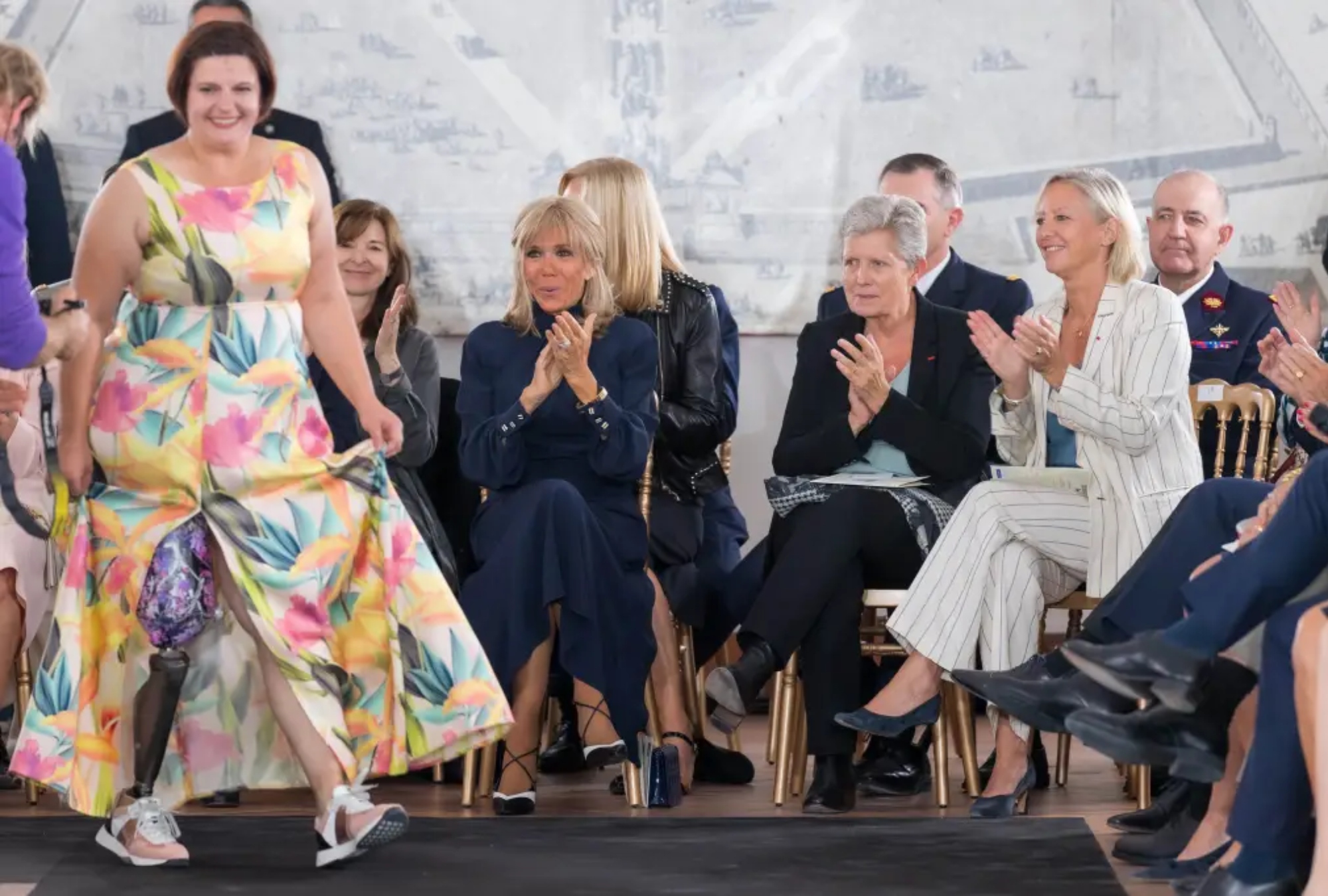 French Defence Minister Florence Parly, French First Lady Brigitte Macron, Secretary of State to the Minister of the Armed Forces Genevieve Darrieussecq and State Secretary for Persons with Disabilities Sophie Cluzel applaud as a model walks the runway during the